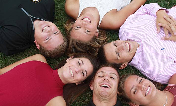 faces of students laying on the ground together